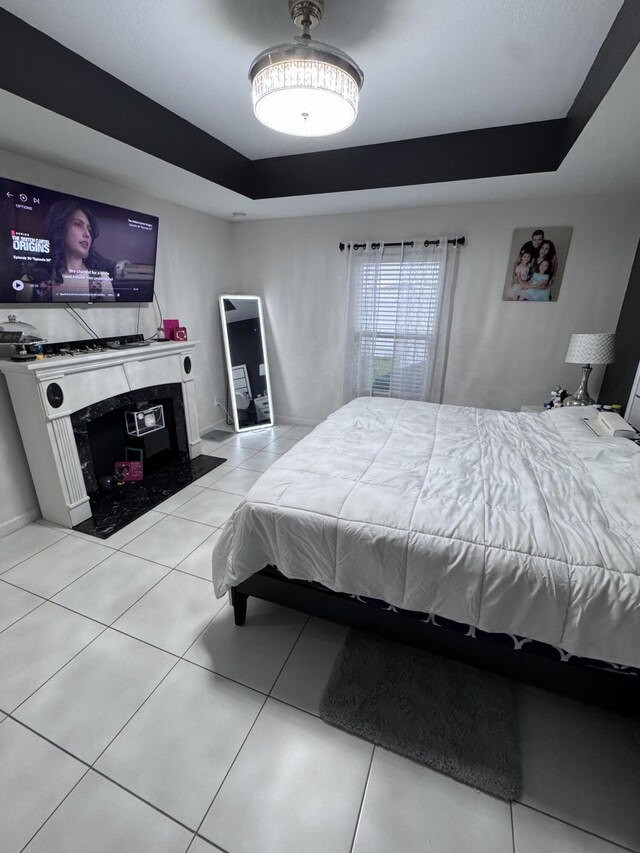 tiled bedroom featuring a raised ceiling and a high end fireplace