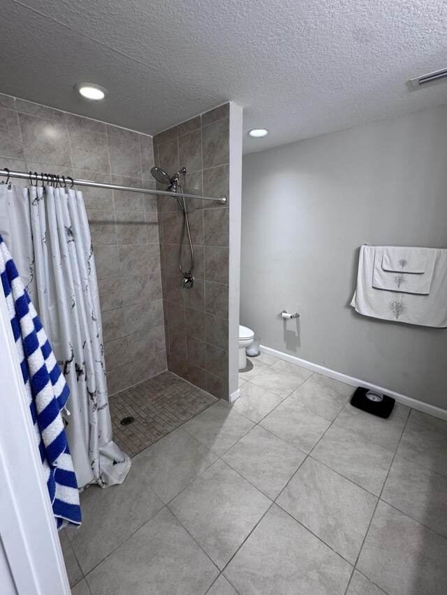 bathroom featuring toilet, tile patterned flooring, a textured ceiling, and a shower with curtain