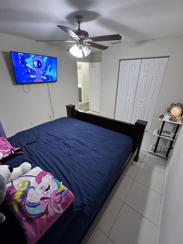 bedroom with ceiling fan, tile patterned floors, and a closet