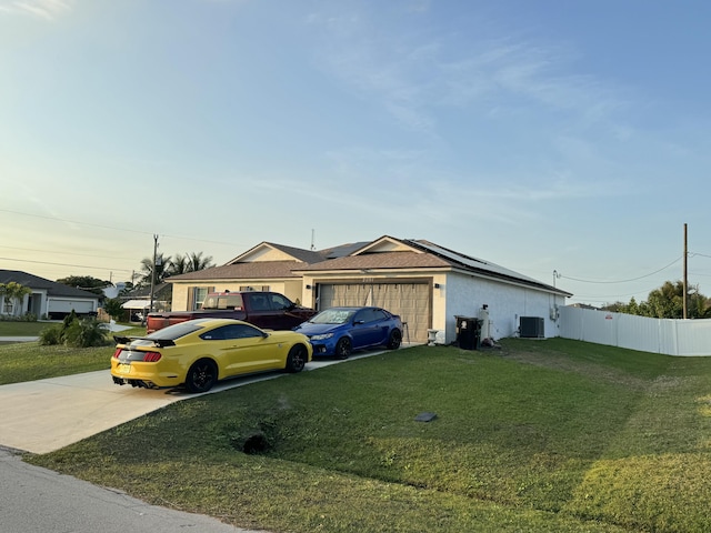 ranch-style home featuring a garage, central AC, and a front lawn