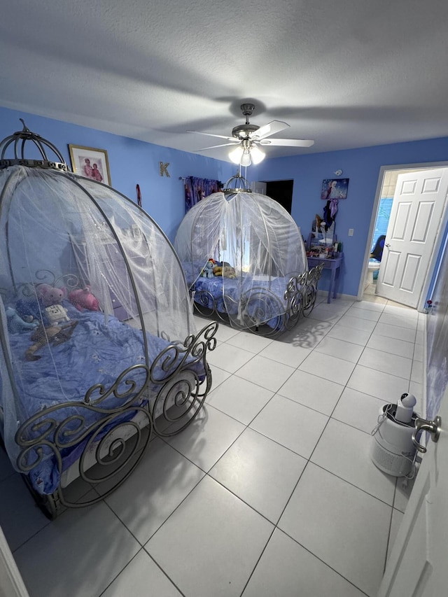 bedroom featuring ceiling fan, connected bathroom, light tile patterned flooring, and a textured ceiling