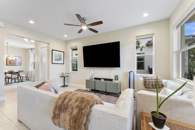 living room with ceiling fan with notable chandelier and light tile patterned floors