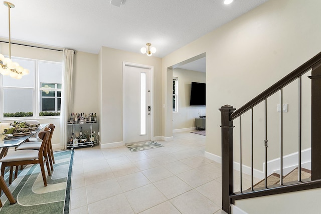 foyer featuring a textured ceiling, light tile patterned flooring, and a notable chandelier