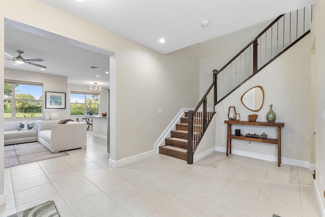 stairway with a textured ceiling, ceiling fan, and tile patterned flooring