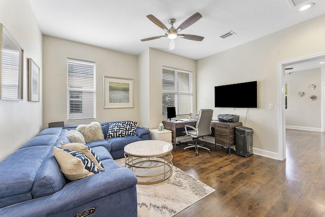 living room with a textured ceiling, dark wood-type flooring, and ceiling fan