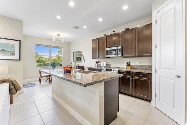 kitchen with a kitchen island with sink, appliances with stainless steel finishes, sink, and light tile patterned flooring