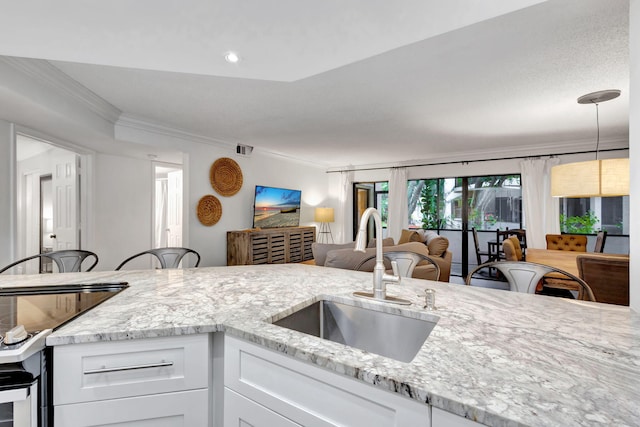 kitchen with white cabinetry, pendant lighting, crown molding, light stone counters, and sink