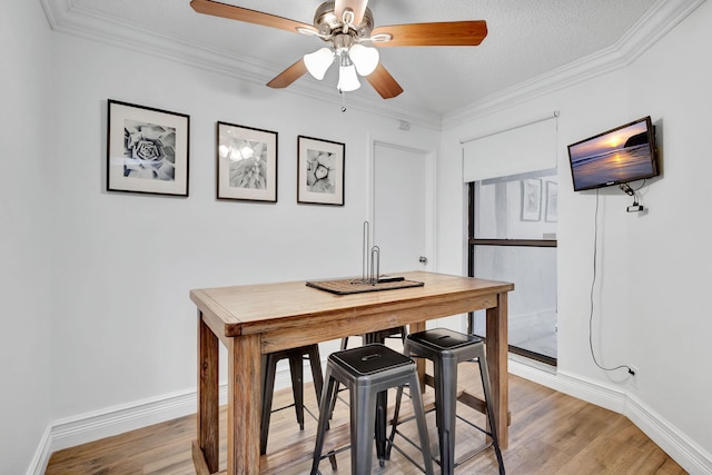 dining area with light hardwood / wood-style floors, a textured ceiling, crown molding, and ceiling fan