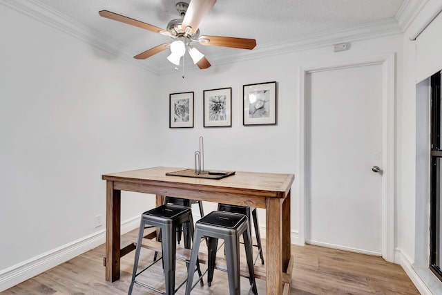 dining area featuring ceiling fan, a textured ceiling, ornamental molding, and light hardwood / wood-style floors