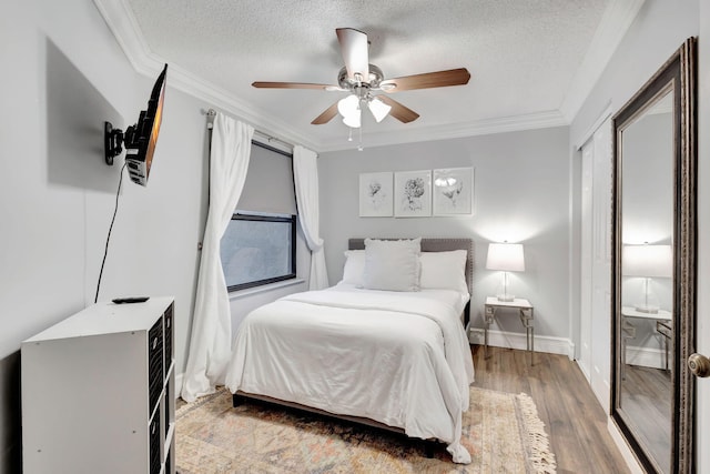 bedroom with ceiling fan, wood-type flooring, ornamental molding, and a textured ceiling