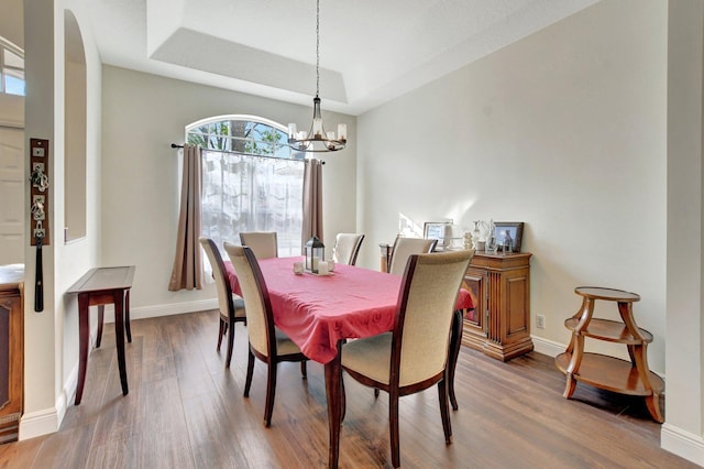 dining room featuring an inviting chandelier, hardwood / wood-style floors, and a raised ceiling