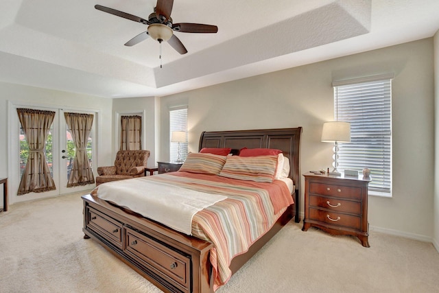 carpeted bedroom featuring ceiling fan, a tray ceiling, and access to outside