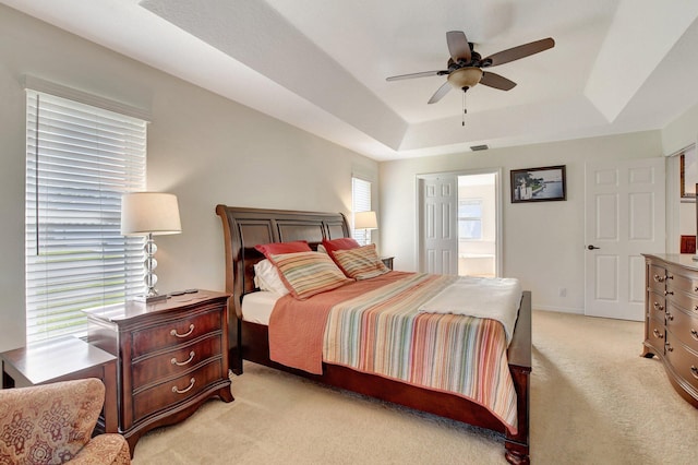 carpeted bedroom featuring ceiling fan, connected bathroom, and a raised ceiling