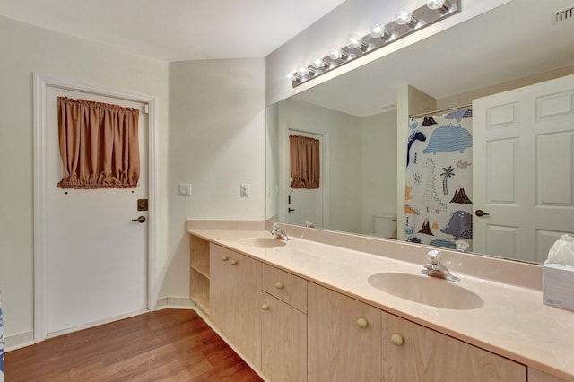 bathroom featuring hardwood / wood-style flooring, vanity, walk in shower, and toilet