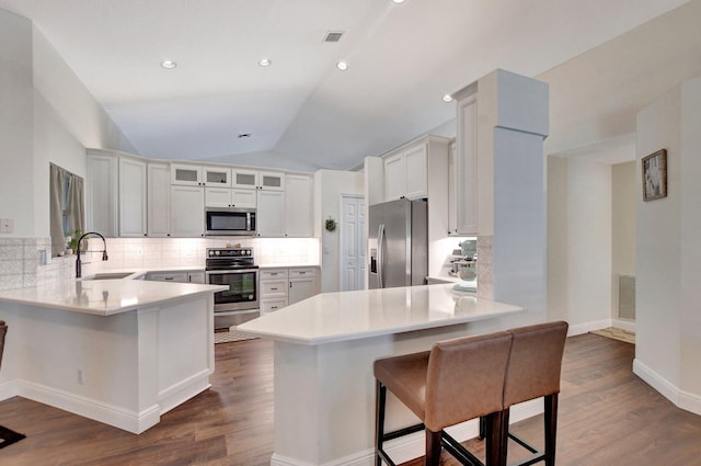 kitchen featuring sink, a breakfast bar area, appliances with stainless steel finishes, white cabinetry, and kitchen peninsula