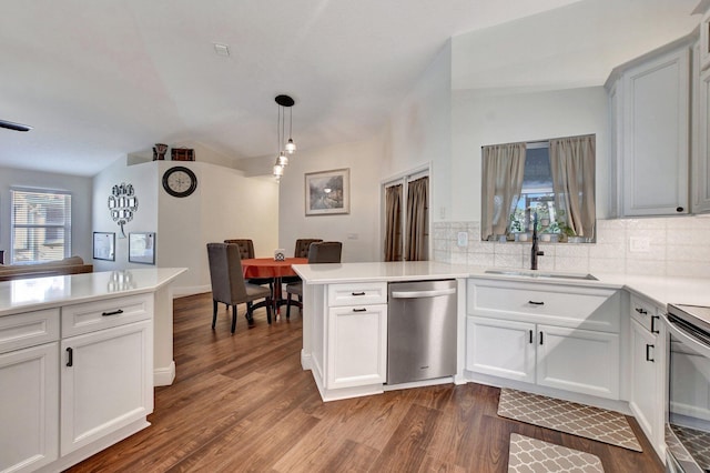 kitchen with sink, dark wood-type flooring, dishwasher, hanging light fixtures, and kitchen peninsula