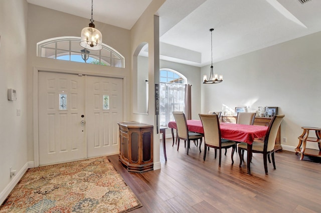 entrance foyer featuring wood-type flooring, a tray ceiling, and a chandelier