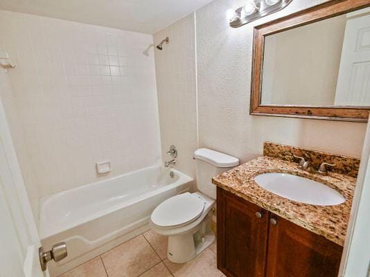 full bathroom with tile patterned flooring, tiled shower / bath, vanity, and toilet