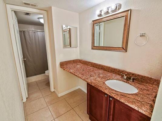 bathroom with tile patterned flooring, vanity, a shower with curtain, and toilet