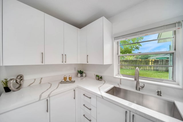 kitchen featuring white cabinetry, light stone countertops, and sink