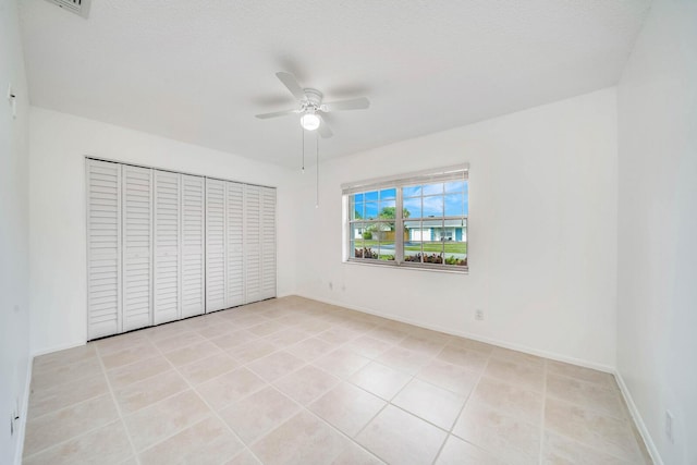 unfurnished bedroom featuring light tile patterned floors, a textured ceiling, and ceiling fan