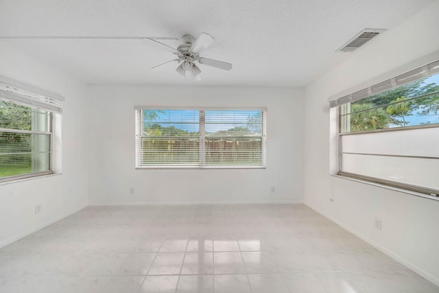 empty room with ceiling fan, a textured ceiling, and a healthy amount of sunlight