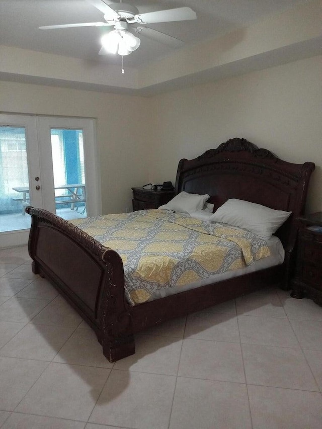 tiled bedroom with ceiling fan, french doors, access to outside, and a tray ceiling