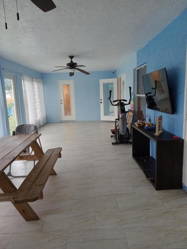 interior space with a textured ceiling and ceiling fan