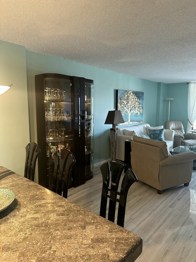 dining space with hardwood / wood-style floors and a textured ceiling