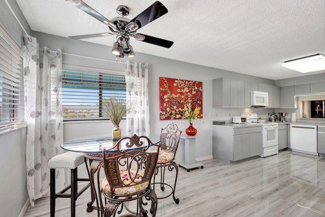 kitchen with light wood-type flooring, a textured ceiling, white cabinets, and white appliances