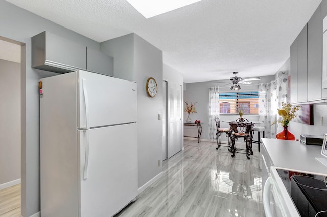 kitchen with gray cabinets, ceiling fan, a textured ceiling, and white appliances