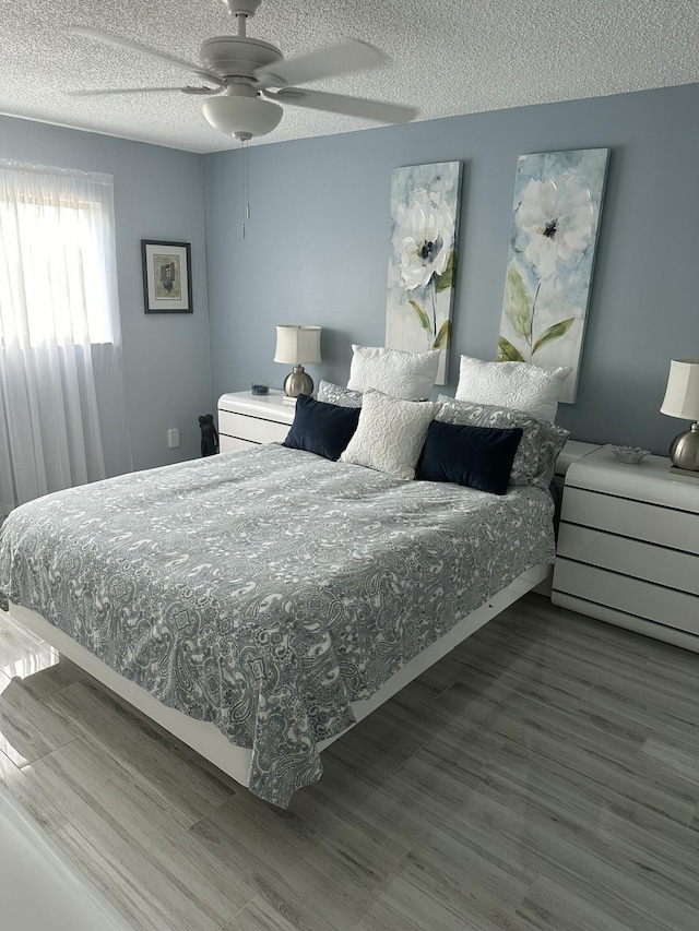 bedroom with hardwood / wood-style floors, a textured ceiling, and ceiling fan