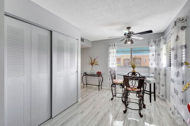 dining room with ceiling fan, a textured ceiling, and light hardwood / wood-style floors