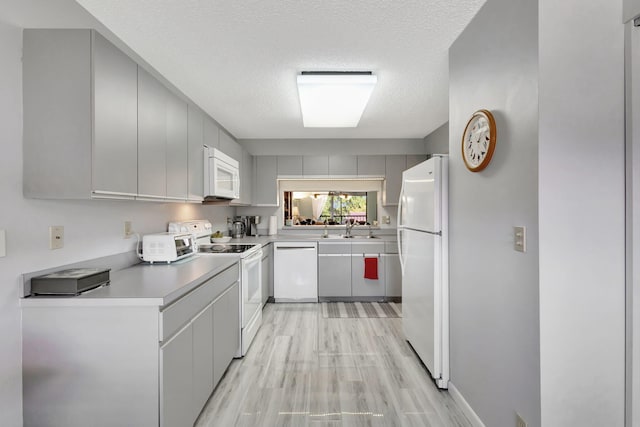 kitchen featuring sink, white appliances, white cabinetry, light hardwood / wood-style floors, and a textured ceiling