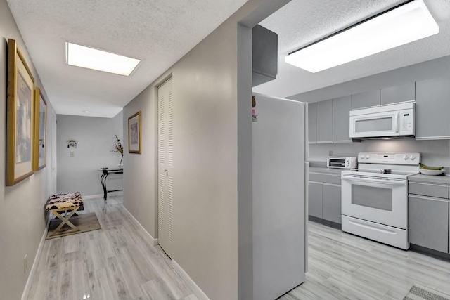 kitchen featuring a textured ceiling, white appliances, and light hardwood / wood-style floors