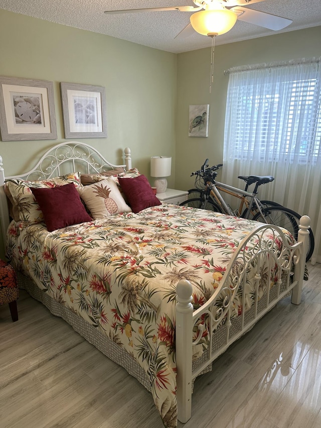 bedroom with a textured ceiling, ceiling fan, and light hardwood / wood-style floors