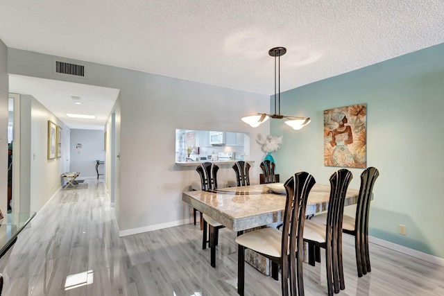 dining room featuring a textured ceiling and light hardwood / wood-style flooring