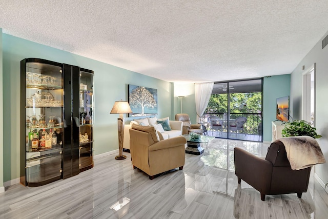 living room featuring expansive windows, light wood-type flooring, and a textured ceiling