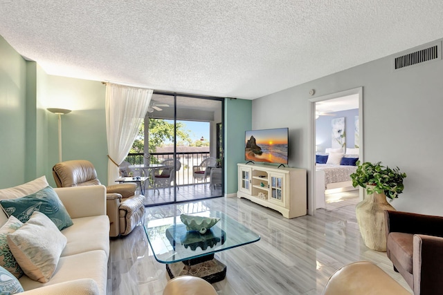 living room featuring floor to ceiling windows, a textured ceiling, and light wood-type flooring