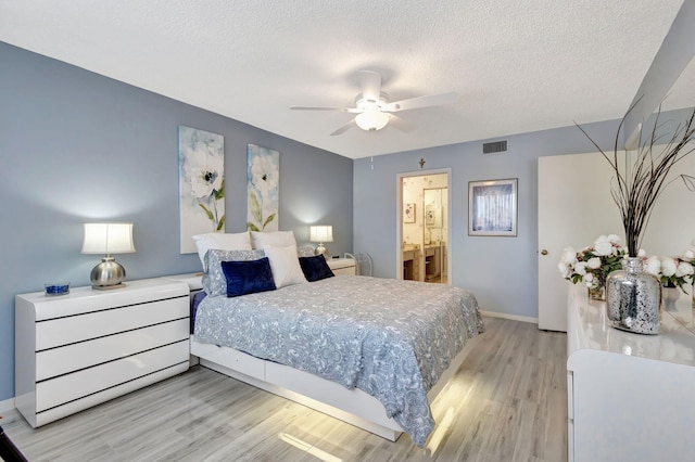 bedroom with ceiling fan, connected bathroom, light hardwood / wood-style floors, and a textured ceiling