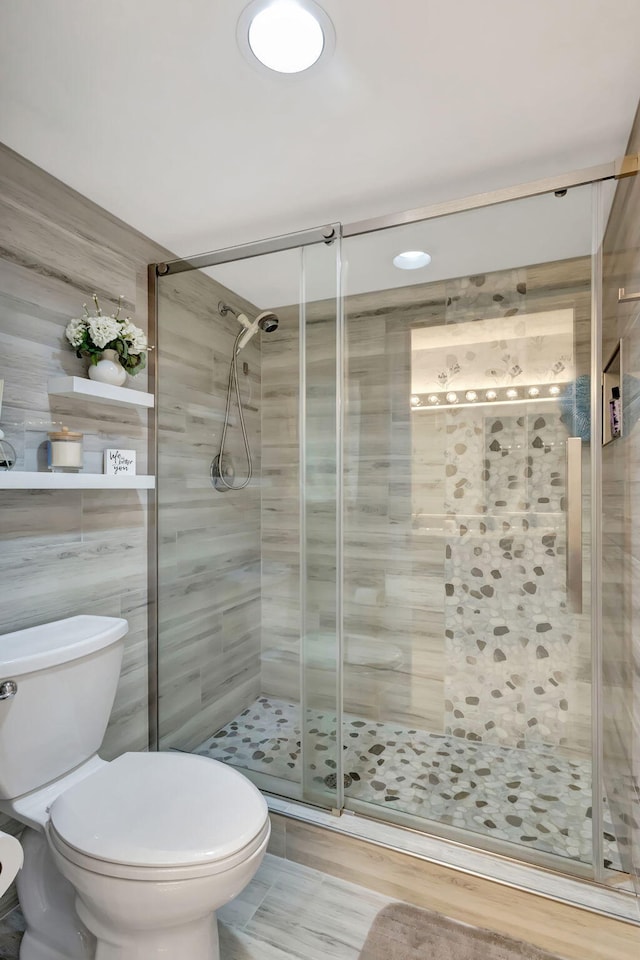 bathroom featuring toilet and a shower with door