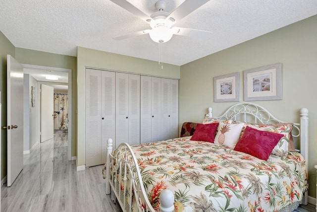 bedroom featuring ceiling fan, light hardwood / wood-style floors, a closet, and a textured ceiling