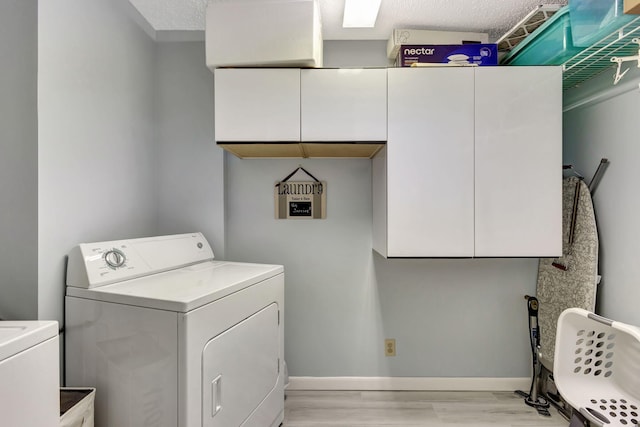 laundry room featuring cabinets, a textured ceiling, washer and dryer, and light hardwood / wood-style flooring