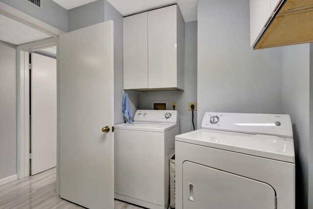 laundry room featuring cabinets, light hardwood / wood-style floors, and washer and dryer