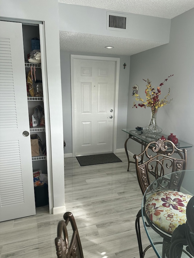 interior space featuring light wood-type flooring and a textured ceiling