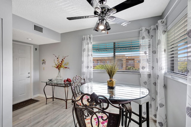 dining area with ceiling fan, a textured ceiling, and light wood-type flooring