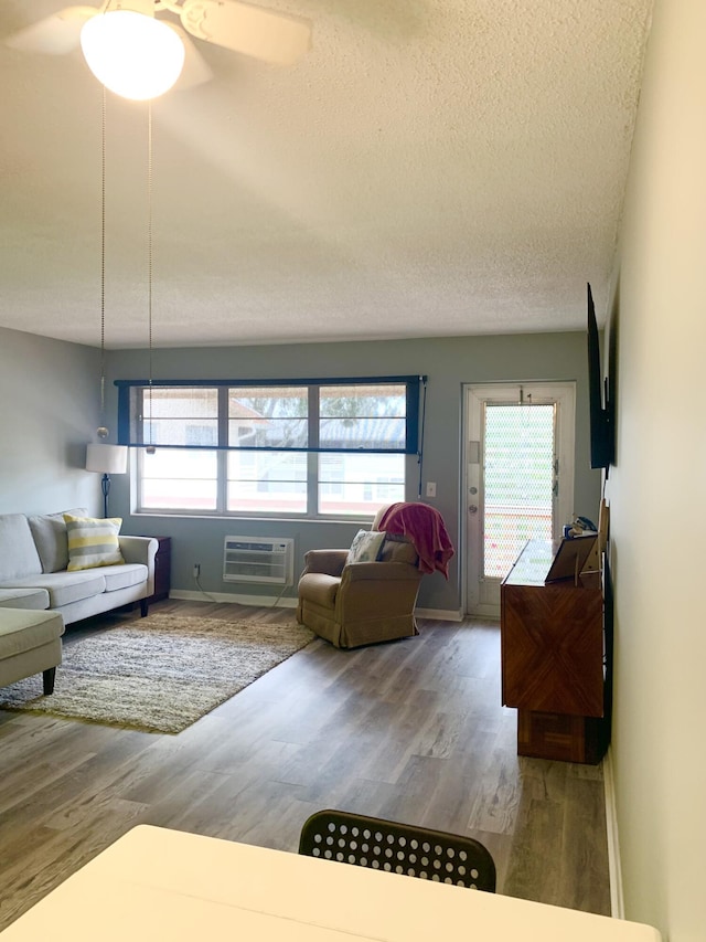 living room featuring hardwood / wood-style flooring, ceiling fan, a textured ceiling, and a wall mounted AC