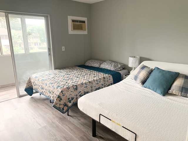 bedroom featuring a wall mounted AC and light hardwood / wood-style floors