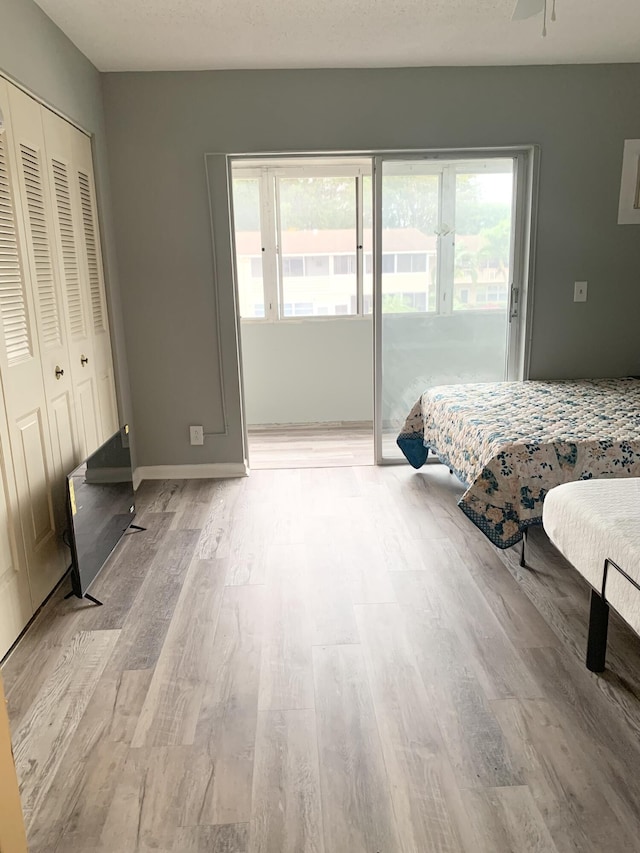 bedroom with a closet, light hardwood / wood-style flooring, access to outside, and ceiling fan