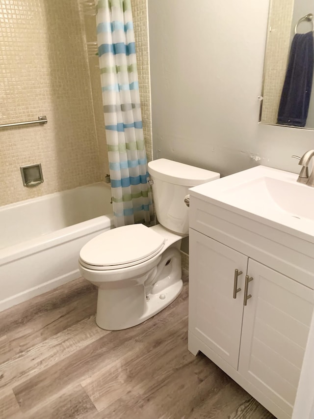 full bathroom featuring toilet, vanity, wood-type flooring, and shower / bathtub combination with curtain